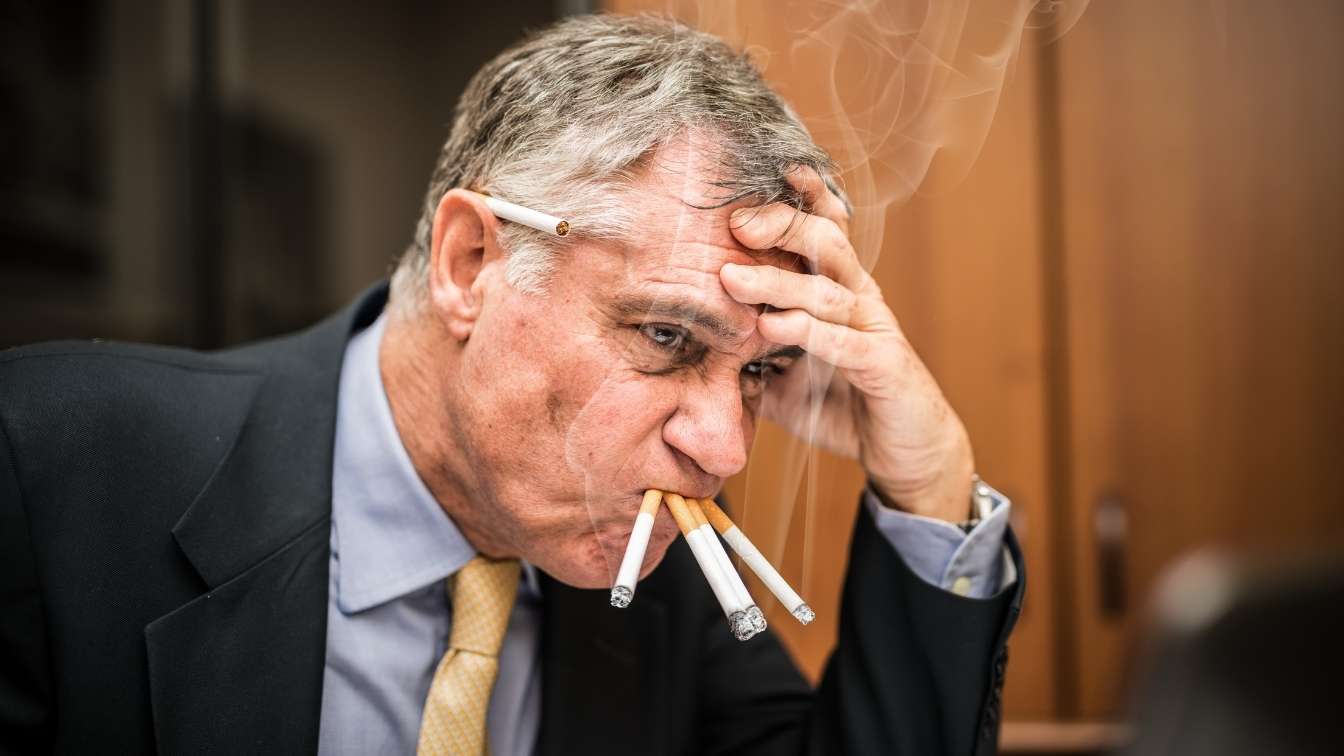 Man looking stressed smoking multiple cigarettes