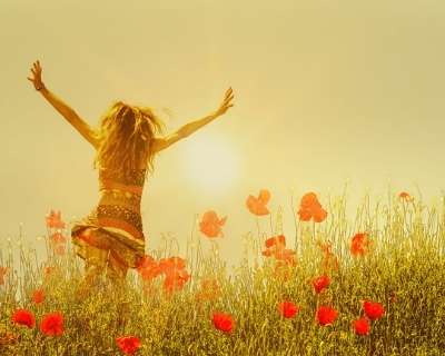 Woman running through poppy field in freedom pose
