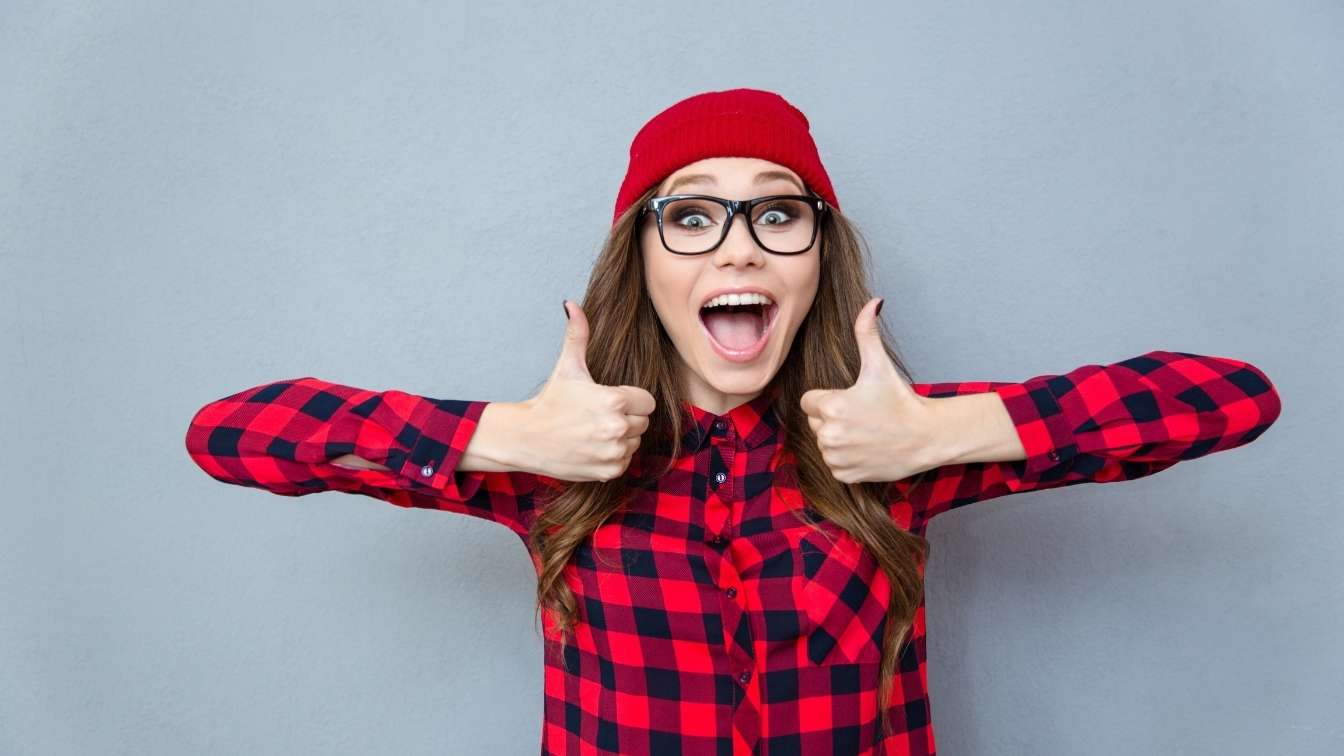 Woman in checked shirt with two thumbs up and happy smile